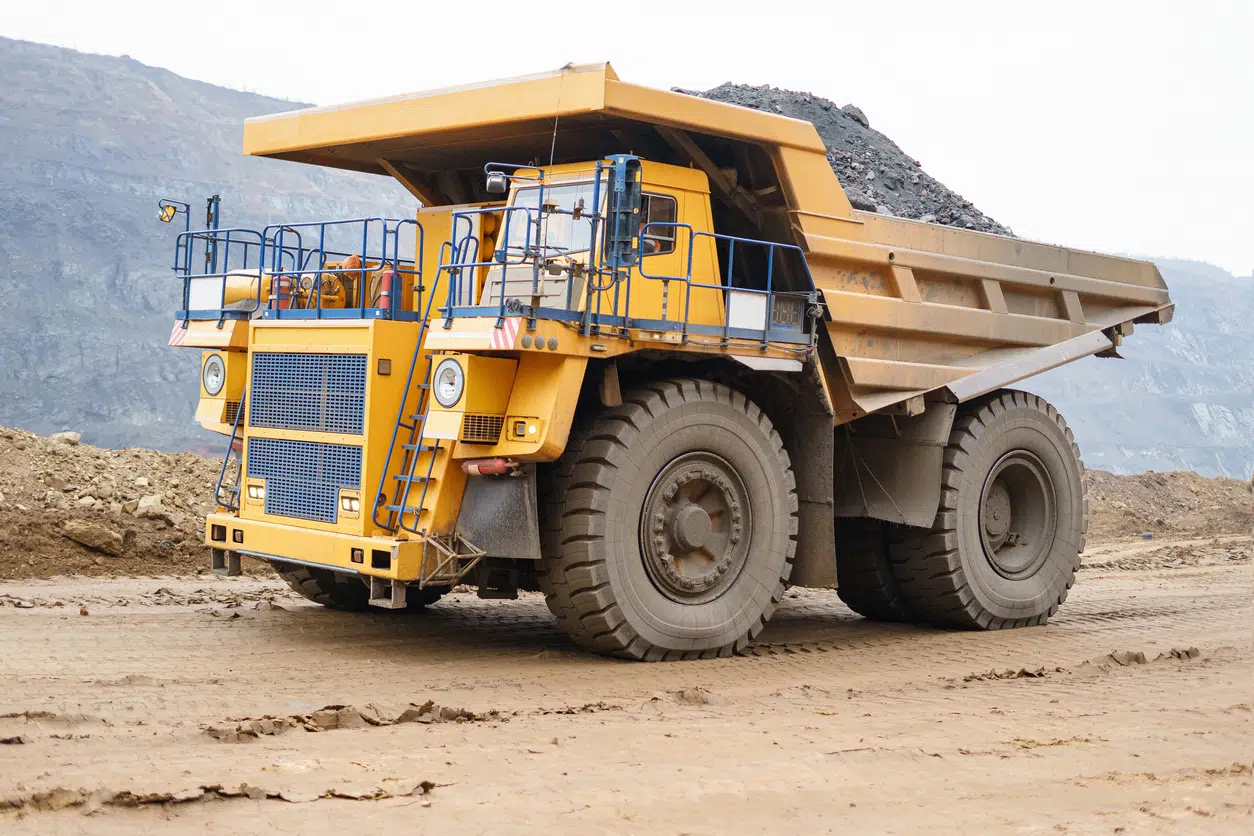 A large open-pit dump truck rides in an open-pit ore quarry. A large open-pit dump truck rides in an open-pit ore quarry. Part of the technological process of open-pit mining.